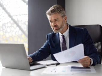 Busy Mature Businessman Working With Laptop And Documents In Office